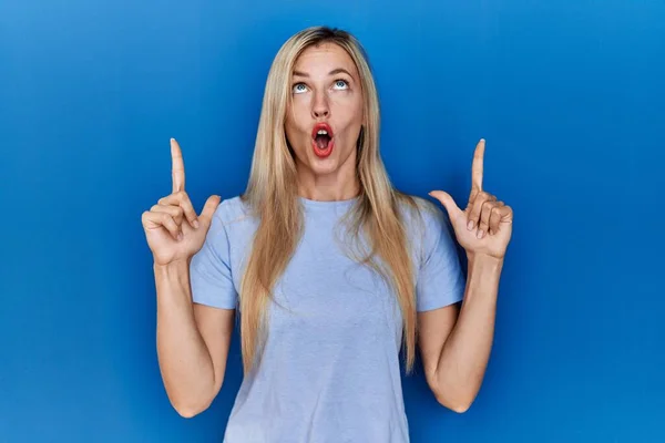 Beautiful Blonde Woman Wearing Casual Shirt Blue Background Amazed Surprised — Stock fotografie