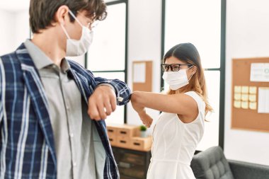 Sağlık maskesi takan iki iş adamı ofiste dirsek koronavirüsü tokalaşması yapıyor..