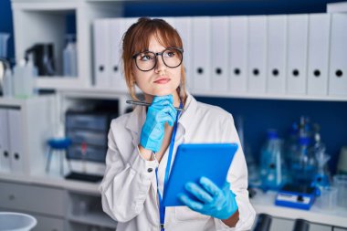 Young woman scientist using touchpad at laboratory