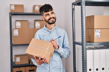Latin kökenli genç bir iş adamı iş yerinde paket üzerine yazıyor.