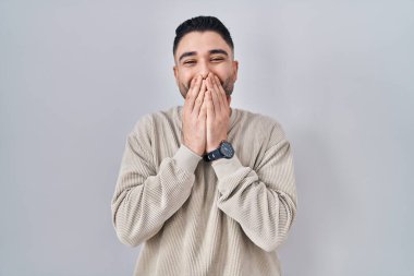 Soyutlanmış arka planda duran genç yakışıklı adam gülüyor ve utanıyor kıkırdıyor elleri, dedikoduları ve skandal kavramlarını ağızlarıyla örtüyor. 