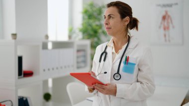 Klinikte dokunmatik ped kullanan İspanyol kadın doktor üniforması giyiyor.