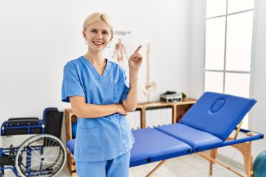 Güzel, beyaz fizyoterapist kadın. Ağrı giderme kliniğinde çalışıyor. Yüzünde kocaman bir gülümseme var.. 