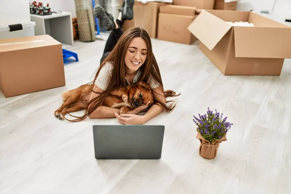 Young Hispanic Woman Using Laptop Lying Floor Hugging Dog New — стоковое фото