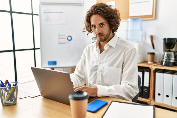 Young hispanic businessman with relaxed expression working at office.