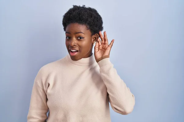 アフリカ系アメリカ人の女性は青い背景の上に立ち 噂やゴシップに耳を傾けながら手で笑っている 聴覚障害の概念 — ストック写真