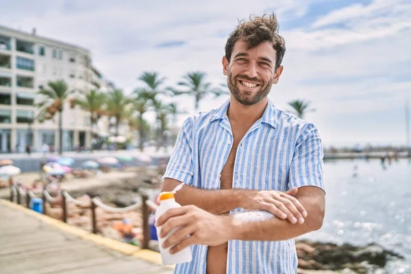 Ung Latinamerikansk Man Ler Glad Med Solkräm Lotion Stranden — Stockfoto