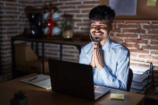 Young Hispanic Man Beard Working Office Night Praying Hands Together — Stockfoto