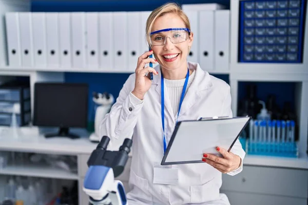 Young Blonde Woman Scientist Talking Smartphone Reading Document Laboratory — Stock Photo, Image