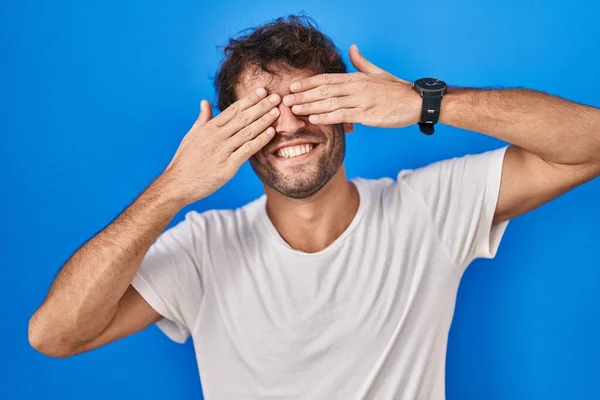 Hispánský Mladý Muž Stojící Nad Modrým Pozadím Zakrývající Oči Veselýma — Stock fotografie