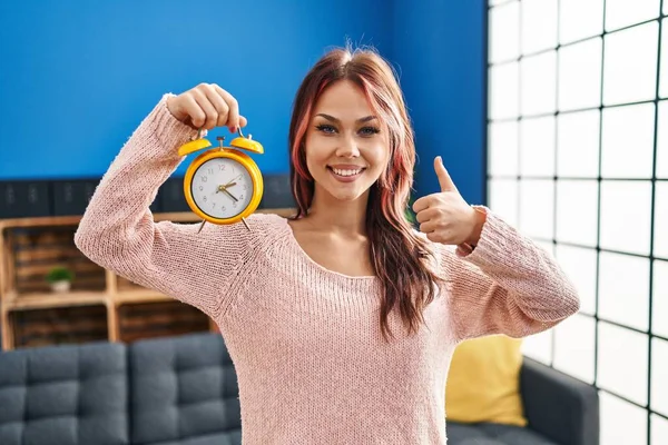Young Caucasian Woman Holding Alarm Clock Smiling Happy Positive Thumb — 图库照片
