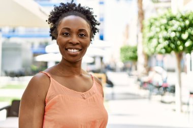 Genç Afrikalı Amerikalı kadın bir yaz günü bar terasında mutlu bir şekilde gülümsüyor.