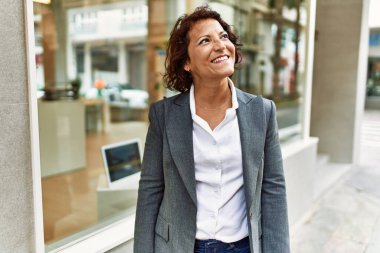 Orta yaşlı Latin iş kadını şehirde mutlu mesut ayakta duruyor..