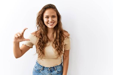 Güzel İspanyol kadın arka planda tek başına dikilirken gülümsüyor ve kendinden emin bir şekilde el hareketi yapıyor parmaklarıyla işaret yapıyor ve kameraya bakıyor. ölçüm kavramı. 