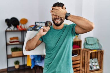 Perakende mağazasında sakallı, alışveriş torbaları tutan, gülümseyen ve gülümseyen genç, yakışıklı bir adam. kör kavram. 