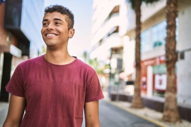 Genç Latin adam gülümseyerek şehirde mutlu mesut dikiliyor..