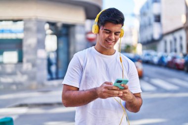 Sokakta müzik dinlerken kendinden emin gülümseyen İspanyol genç adam.