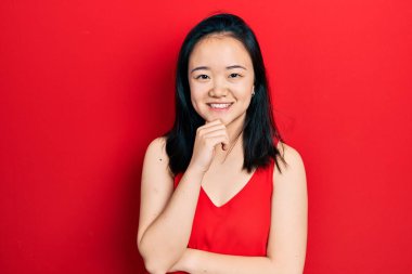 Young chinese girl wearing casual clothes smiling looking confident at the camera with crossed arms and hand on chin. thinking positive. 