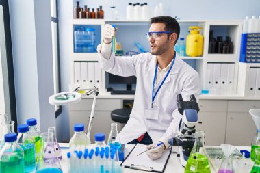 Laboratuvarda test tüpleri tutan genç İspanyol bilim adamı rapor yazıyor.