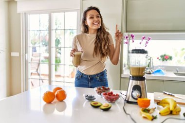 Mutfakta bir bardak smoothie içen güzel, genç esmer kadın bir fikir ya da soru işareti ile şaşırdı. 