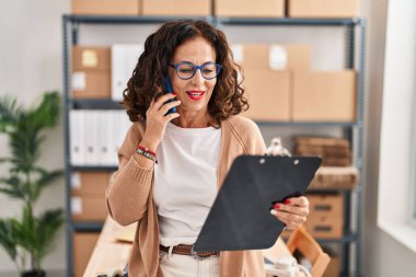 Middle age hispanic woman working speaking on the phone at ecommerce
