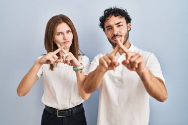 Gündelik giysiler giyen genç bir çift yan yana duruyor. Reddedilme ifadesi olumsuz işaret veriyor. 
