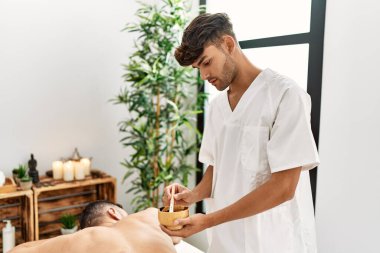 İki İspanyol erkek fizyoterapist ve hasta güzellik merkezinde cilt bakımı yaptırıyor.