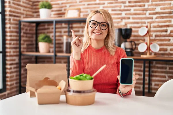 Blonde Frau Beim Essen Zum Mitnehmen Zeigt Smartphone Bildschirm Glücklich — Stockfoto