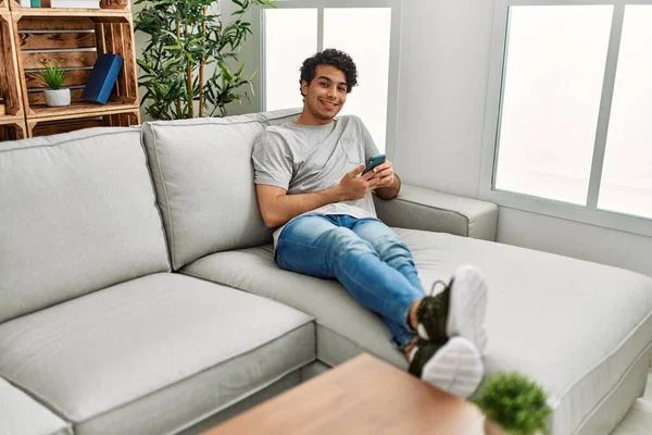 Ung Latinamerikan Man Med Smartphone Sitter Soffan Hemma — Stockfoto