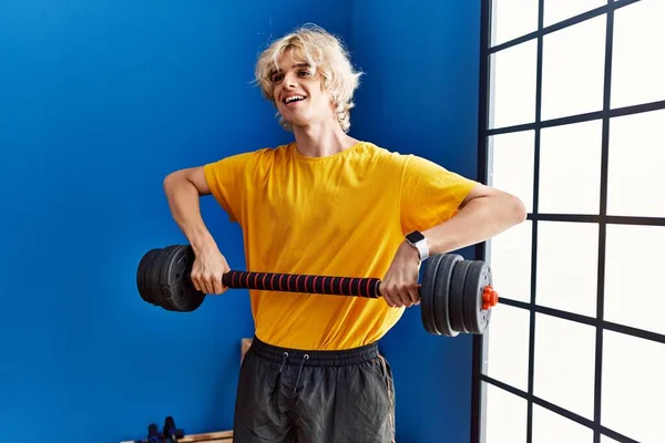 Young blond man smiling confident using weight training at sport center
