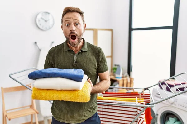 Middle Age Man Holding Folded Laundry Ironing Afraid Shocked Surprise — Stockfoto