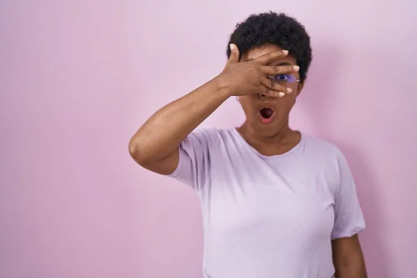 Jovem Afro Americana Sobre Fundo Rosa Espreitando Choque Cobrindo Rosto — Fotografia de Stock