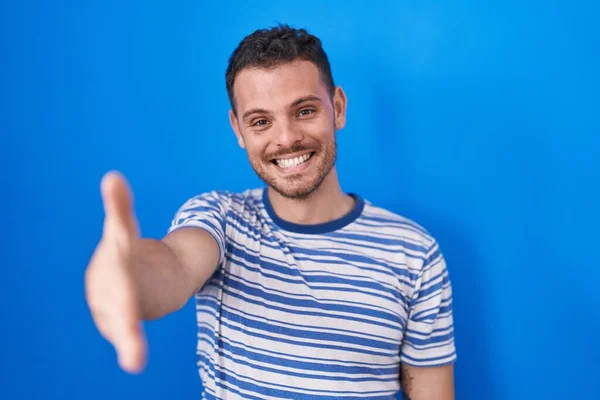 Jovem Hispânico Sobre Fundo Azul Sorrindo Amigável Oferecendo Aperto Mão — Fotografia de Stock
