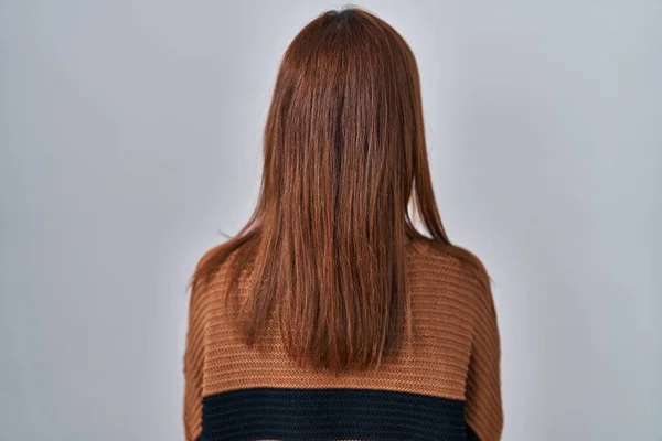 年轻美丽的女人穿着条纹毛衣站在与世隔绝的背景上 背向后看去 交叉着双臂 — 图库照片