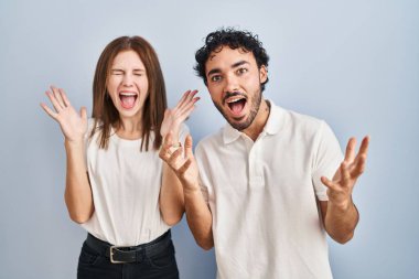 Gündelik giysiler giymiş genç bir çift çılgın ve başarıyı kutlarken kolları açık ve gözleri açık heyecanlı bir şekilde haykırıyorlar. Kazanan konsept 