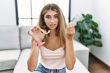 Genç sarışın kadın, görünmez hizayı tutuyor, italyan jesti yapıyor, elleriyle ve parmaklarıyla kendinden emin ifade ediyor. 