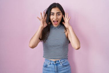 Young teenager girl wearing casual striped t shirt celebrating crazy and amazed for success with arms raised and open eyes screaming excited. winner concept 