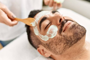 Genç İspanyol adam güzellik merkezinde yüz maskesi tedavisi görüyor.