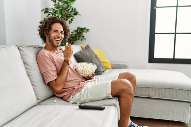 Evdeki kanepede oturmuş film izleyen İspanyol genç adam..