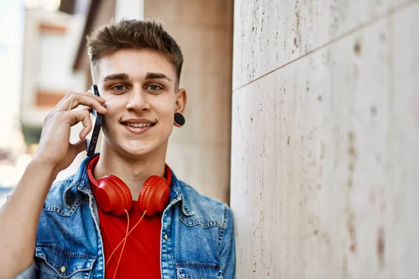 Joven Chico Caucásico Sonriendo Con Teléfono Inteligente Apoyado Pared — Foto de Stock