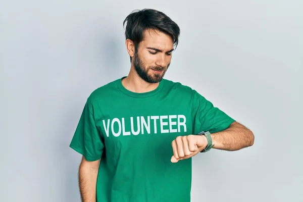 Jovem Hispânico Vestindo Camiseta Voluntária Verificando Tempo Relógio Pulso Relaxado — Fotografia de Stock