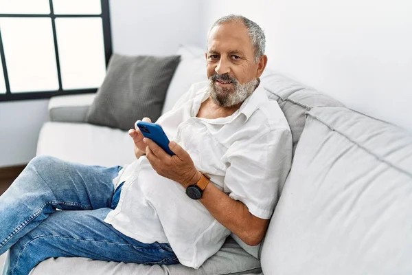 Älterer Grauhaariger Mann Lächelt Selbstbewusst Mit Smartphone Hause — Stockfoto