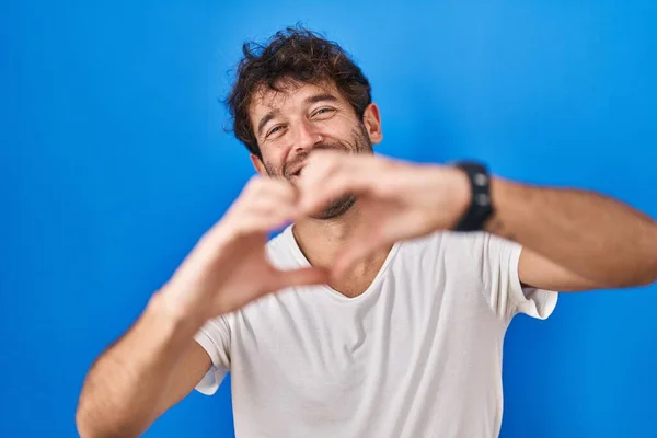 Spaanse Jongeman Die Een Blauwe Achtergrond Staat Glimlachen Liefde Hartsymbool — Stockfoto