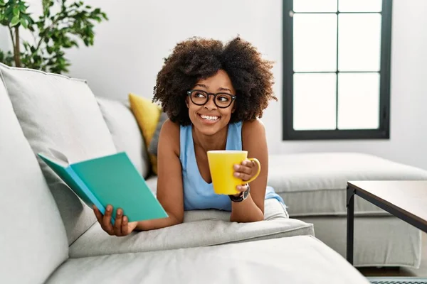Νεαρή Αφροαμερικανή Γυναίκα Που Πίνει Καφέ Διαβάζοντας Βιβλίο Στο Σπίτι — Φωτογραφία Αρχείου