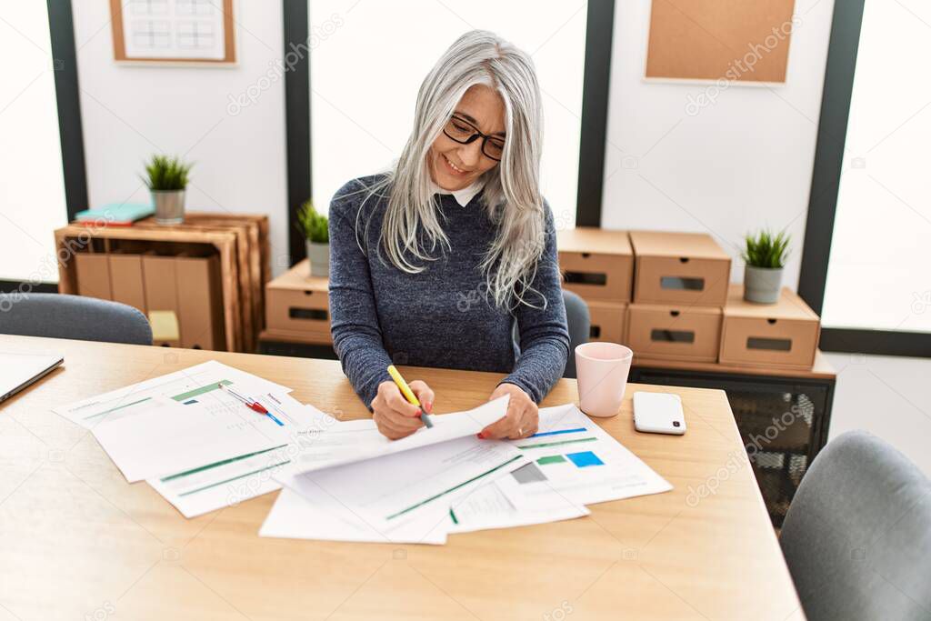 Middle age grey-haired woman business worker smiling confident working at office