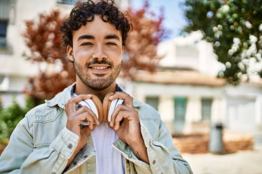 Yakışıklı, sakallı, neşeli, güneşli bir günde kulaklık takan bir İspanyol.