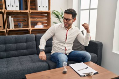 Danışma ofisinde sakallı, neşeli ve mutlu dans eden, gülümseyen, rahat ve kendinden emin müzik dinleyen genç İspanyol bir adam. 