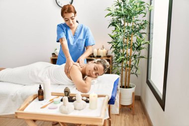 Kadın çift güzellik merkezinde sırt masajı yaptırıyor.