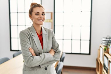 Young woman business worker standing with arms crossed gesture at office