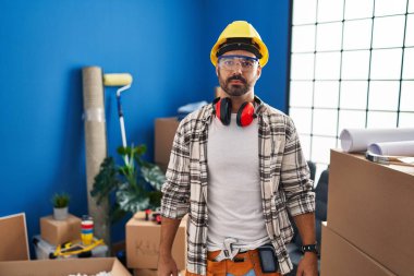 Evde çalışan sakallı İspanyol genç adam yüzünde ciddi bir ifadeyle rahatladı. Basit ve doğal bir şekilde kameraya bakıyorsun.. 